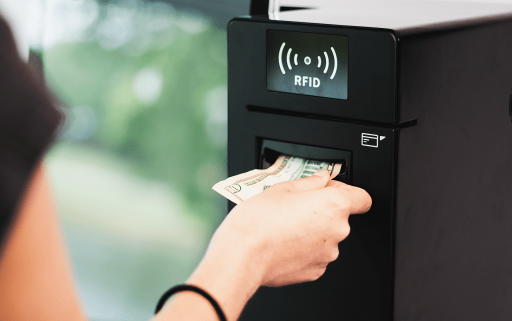 Photo of person loading the Volanté Systems CashLink Kiosk with a 10-dollar bill. The CashLink Kiosk is a point-of-sale hardware solution that allows users to load cash into their accounts.